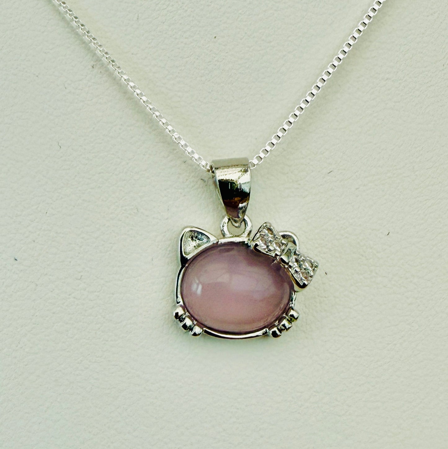 Cat face-shaped pendant with pink gemstone and silver chain