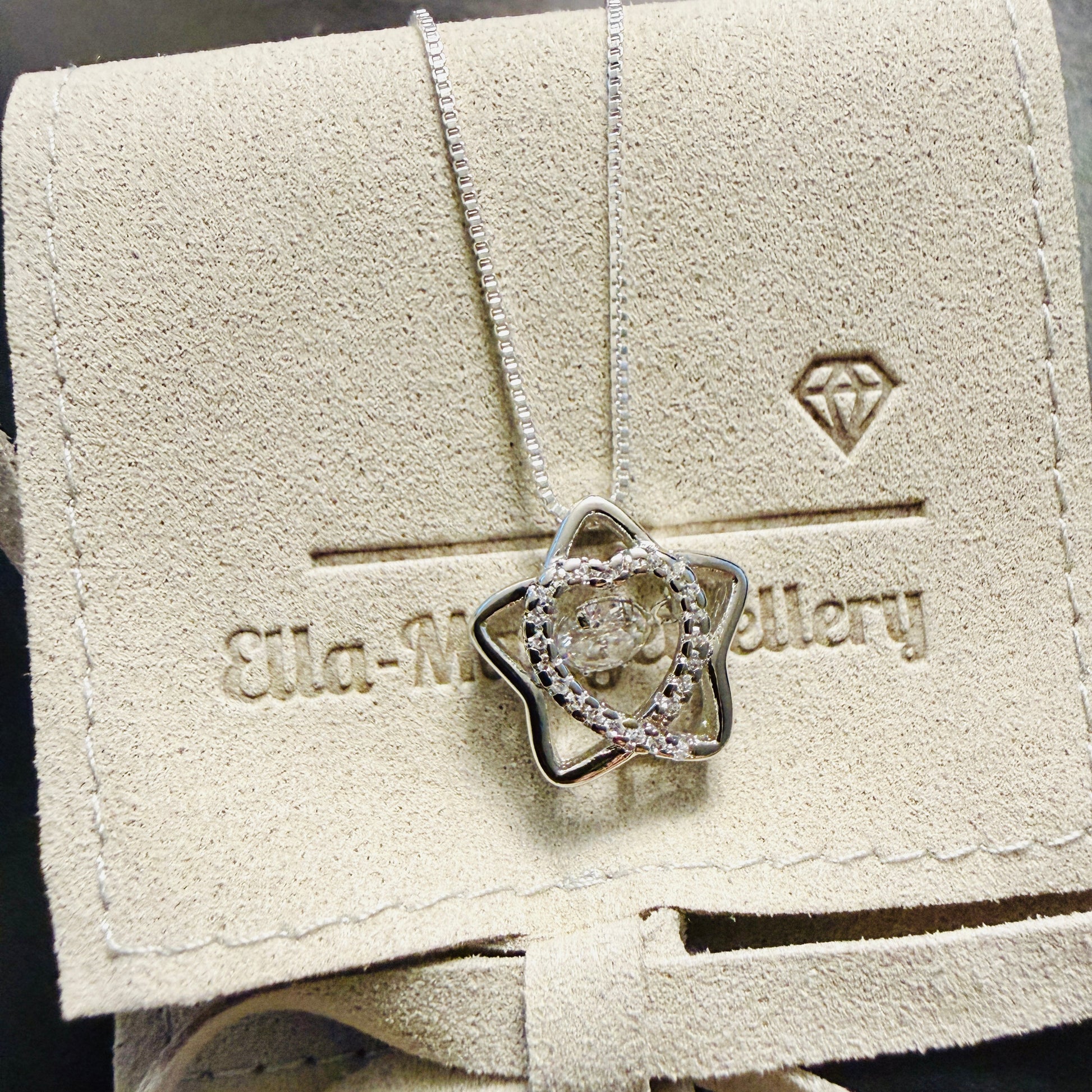 Star shaped pendant with crystal inner heart and dancing inner crystal on luxury gift pouch