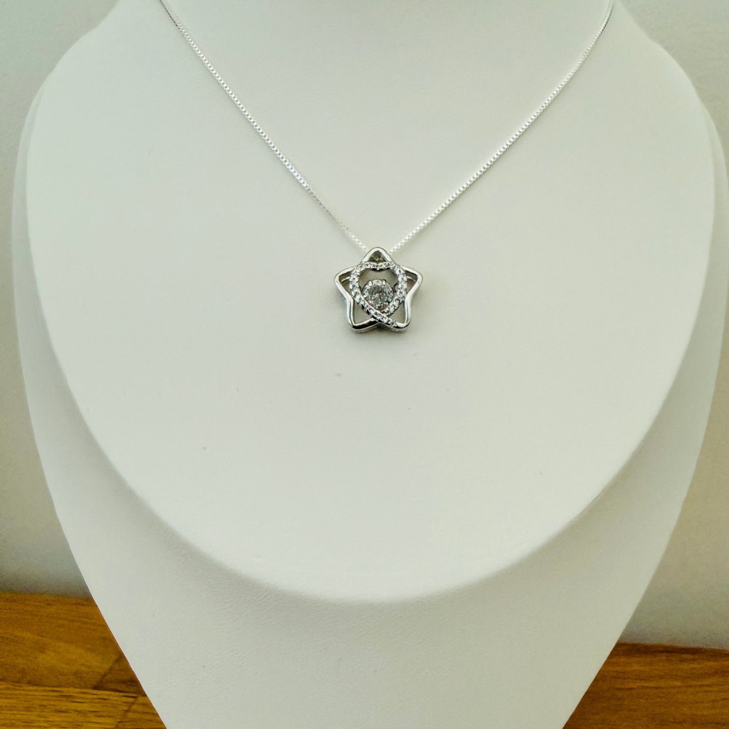 Silver crystal necklace with a star-shaped pendant on a white stand.