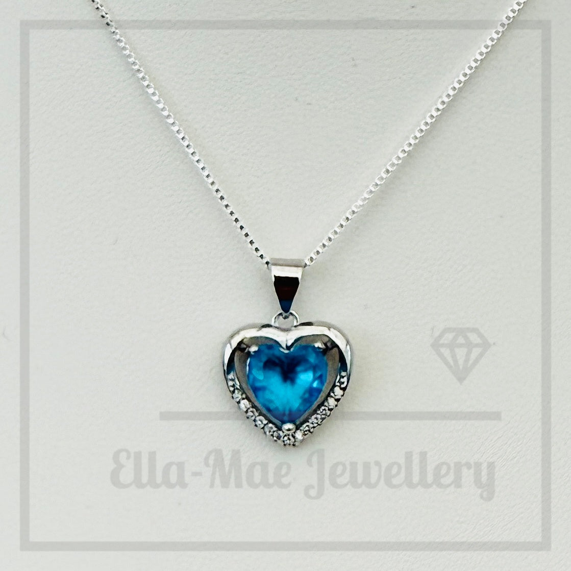 Azure blue heart-shaped crystal pendant on a silver chain with 'Ella-Mae Jewellery' branding.